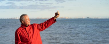 Son sınıf öğrencisi elektrikli dağ bisikletiyle selfie çekiyor. Denizin gerisinde fotokopi sağda asılı duruyor. konsept gençliğini kaybetmeden yaşlanıyor.