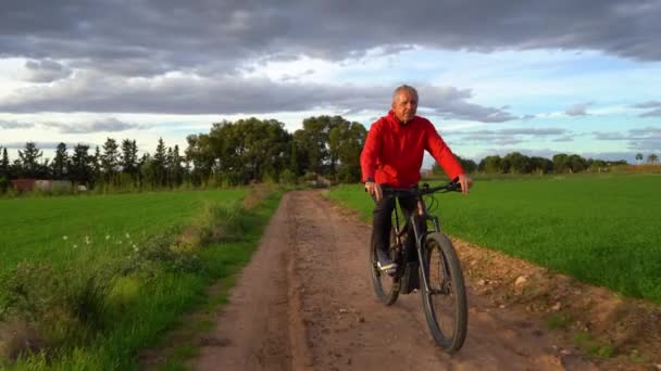 Idősebb Férfi Elektromos Hegyi Biciklivel Sportol Zöld Mezőn Keresztül Úton — Stock videók