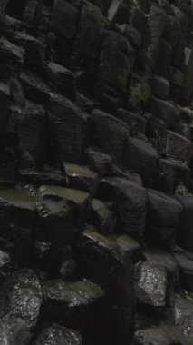 Bazaltik prizmaların hava dikey videosu. Seyahat ve tatil konsepti. Dikey doğa videosu. Bazaltik prizmaların 4k dikey videosu