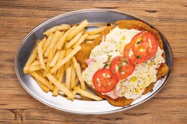 Overhead view of a plate of Neapolitan Milanese with French fries. Argentinian food concept. Gourmet food