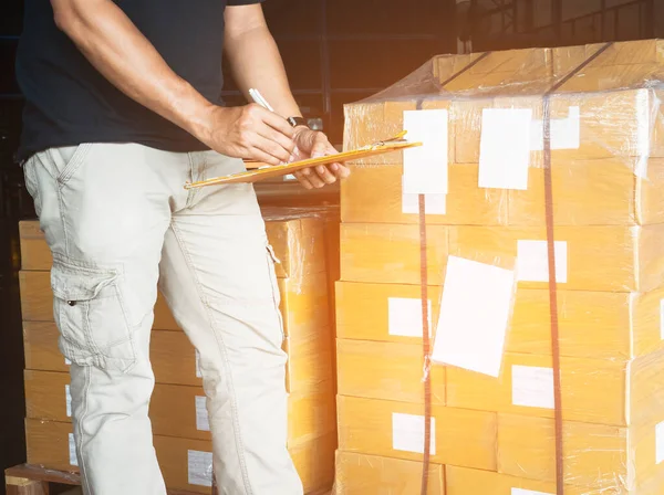 作業者クリップボードを保持している作業者は倉庫の梱包箱をチェックしています 在庫管理サプライチェーン 出荷箱 配送倉庫物流 — ストック写真