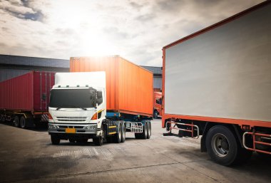 Deponun otoparkındaki yarı karavan kamyonları. Rıhtım deposunda kamyonlar yükleniyor. Kargo konteynırı nakliye kamyonları. Dağıtım Deposu. Yük Kamyonları Lojistik, Kargo Taşımacılığı.