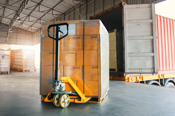 Package Boxes Wrapped Plastic Stacked on Pallets and Hand Pallet Truck. Loading Dock Warehouse. Supply Chain Warehouse Shipping Freight Truck Logistics.