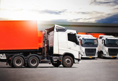 Deponun otoparkındaki yarı karavan kamyonları. Depo 'da kamyon dolusu mal var. Konteynır nakliyesi. Traktör kamyonu. Kamyonculuk. Lorry Diesel Trucks. Nakliye Aracı Lojistik Kargo Taşımacılığı.