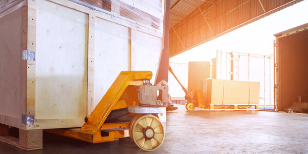 Деревянные ящики и ручная тележка для поддонов. Погрузка груза в контейнерные грузовики в доке Хранилища. Дистрибутив Склад Доставка, Цепь поставок, Отгрузка. Грузовые перевозки грузовых автомобилей.