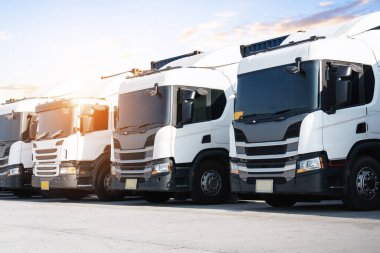 Depo Limanı 'ndaki otoparkta yarı kamyonlar. Kargo konteynırı nakliyesi. Ekonomik İş Taşımacılığı Yolda. İçeri- Dışarıya aktar. Kamyonculuk. Lorry Diesel Truck. Yük Lojistik Taşımacılığı.