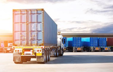 Depo Limanı 'ndaki otoparkta yarı karavan kamyonları. Rıhtım deposunda yük kamyonu var. Dağıtım Deposu Merkezi. Konteynır nakliyesi. Nakliye Aracı Lojistiği, Kargo Taşımacılığı.