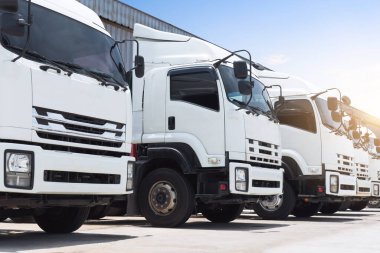 Depodaki otoparka park etmiş kamyonlar. Big Rig, Nakliye Kamyonları, Dağıtım Deposu. Ekonomik İş Taşımacılığı Yolda. Kamyonculuk. Nakliye Aracı Taşımacılığı.