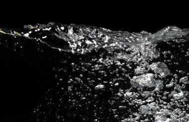 Siyah üzerine su sıçrıyor. Hava kabarcıkları suda yüzer. Su Dalgası. Siyah Arkaplanda Saf Su.