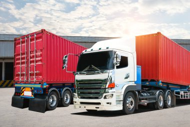 Deponun otoparkındaki yarı karavan kamyonları. Kargo konteynırı. Rıhtım deposunda yük kamyonu var. Dağıtım Deposu. İthalat-ihracat. Nakliye Aracı Taşımacılığı.