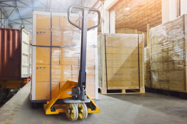 Bir sürü paket kutusu konteynır kamyonlarına yüklenmeyi bekliyor. Forklift Palet Jack. Dağıtım Deposu, kargo konteynırı. Nakliye Aracı Lojistik Taşımacılığı.