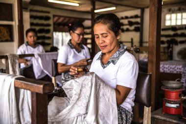 Bali - Indonesia - 10.22.2015: Elderly indonesian women applying wax on batik in a touristic atelier