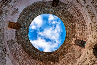 Ruins of the old city. View of the sky with clouds from the bottom up from inside the stone Tower in the opening of the round ceiling, geometric arches and doorways of the Diocletian's palace, viewed from a low position. Split old town, Croatia
