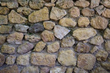 Bej, ahşap ve kahverengi taşlardan yapılmış eski kaba panoramik taş duvar.