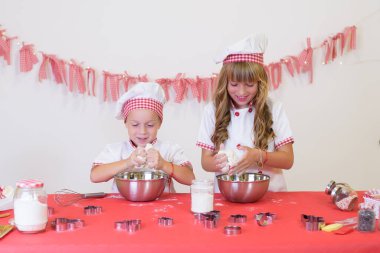Önlüklü mutlu çocuklar ve un, yumurta, çikolata ve suyla kurabiye pişiren şef şapkalı çocuklar. Mutfak ve aile. Mutlu çocuklar..