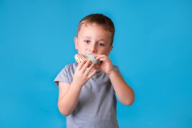 Sarı saçlı, çilli ve jöleli çörek yiyen şirin bir çocuk. Çocuklar ve şekerli abur cubur konsepti. Çocuk renkli çörekler tutuyor, şekerli abur cubur yiyor..