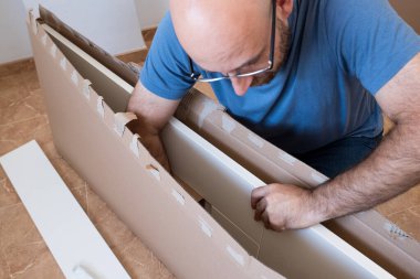 The man assembling new furniture in his house. clipart