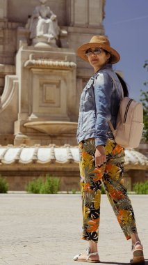 Genç bir bayan turist bir yaz öğleden sonra bir meydanda heykelin önünde.