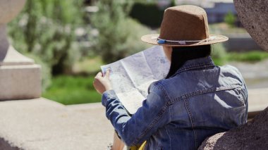 Genç turist bir köprüde oturuyor. Bir yaz öğleden sonra elinde haritayla dinleniyor..