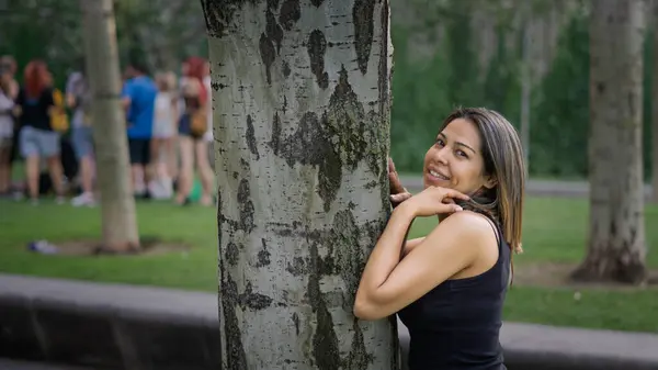 Happy young woman hugging a tree while smiling