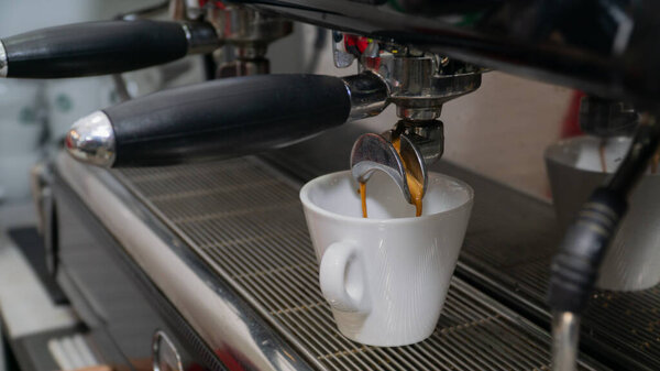 espresso machine coffee brewing in a white cup