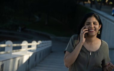 Bir kadın merdivenlerden inerken cep telefonuyla konuşuyor. Gülümsüyor ve sohbetten zevk alıyor.