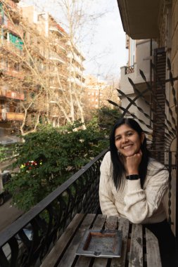 Bir kadın bankta onunla oturuyor. Gülümsüyor ve şehre bakıyor.