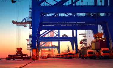 Konteynır gemisinin yanında bekleyen kamyon filosu konteynır kutusunu iç kısımlara götürmek için bekliyor.