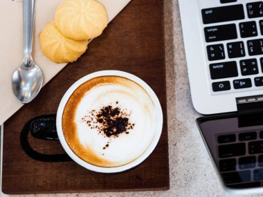 Sabah kahvesi ve kurabiye laptopun yanında, serbest çalışan masa.