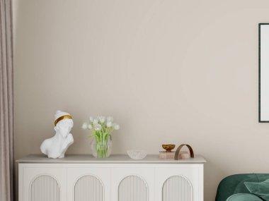 Modern oturma odası yeşil kadife kanepe, bej duvarlar, iki boş çerçeve, beyaz sehpa ve dekoratif eşyalarla dolu beyaz bir dolap. Tarafsız tonlar ve minimalist estetik hoş ve zarif bir ortam yaratır..