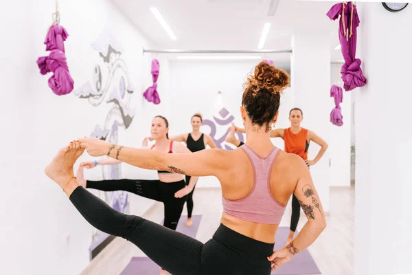 yoga teacher teaching her female students a pose during a yoga class in studio. sport and healthy lifestyle