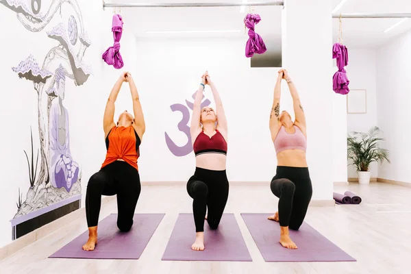 three women of different ages practicing yoga during a class in a studio. warrior pose. body and mind. sport and healthy lifestyle. \
