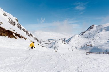 Unrecognizable person in yellow jacket skies down a snowy mountain on a ski slope. winter sports.