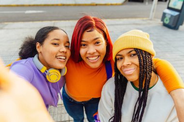Three latina girls taking a selfie on the street. Women with unretouched skin. celebrating friendship.
