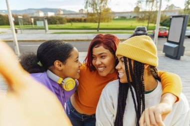 three young hispanic girls taking a picture as they leave class. latina friends celebrating friendship.