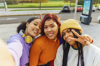 Three latina girls taking a selfie on the street. Women with unretouched skin. celebrating friendship.