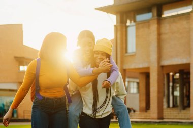 Bir grup genç kız, dersten sonra üniversitede ya da lisede eğleniyorlar. Gün batımında birlikte gülen kadınlar. Arkadaşlık ve birlik kavramı. sınıfların sonu