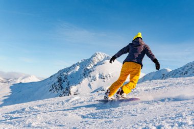 Sarı elbiseli, güneşli bir günde kar kayağı antrenmanı yapan tanınmamış biri. kış ve dağ sporları konsepti.