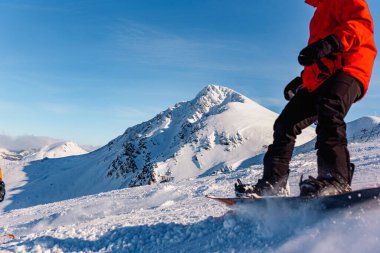 Karlı dağ manzarası. Ön planda kırmızı giysiler içinde çözünmüş kar aracı var. kış sporları