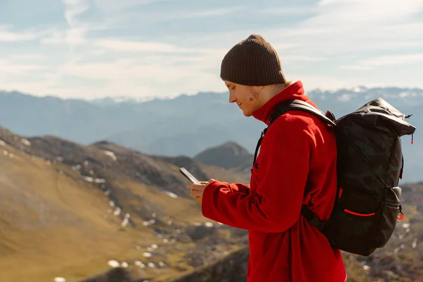 stock image White male mountaineer, with a backpack, using a GPS application on his smartphone to orient himself in the mountains. caucasian man using the mobile in the mountain.