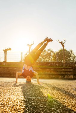 Beyaz çocuk sokakta breakdance yapıyor. Sokakta gün batımında amuda kalkıyor. Sokak dansçısı. gençlik kültürü ve hip-hop
