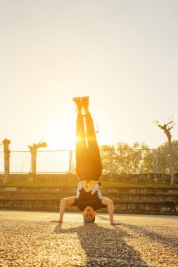 Sokak dansçısının akrobatik hareketlerini gösteren dikey bir fotoğraf. Genç çocuk sokakta break dans yapıyor. Gençlik kültürü. hip-hop.