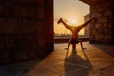 Gün batımında sokakta dans eden genç bir çocuğun arka ışıklandırılmış silueti. Gençlik kültürü ve hip hop. Sokak dansçısı.