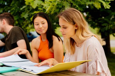 İki kız, biri beyaz, biri Asyalı, diğer sınıf arkadaşlarıyla aynı masada oturuyorlar. kolej hayatı.