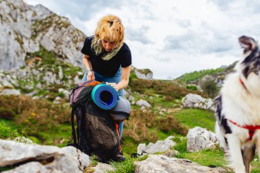 Genç beyaz kadın, yürüyüşçü ve sırt çantasıyla birlikte köpeğiyle dağlarda yürüyüşe hazırlanıyor. picos de europa Ulusal Parkı, asturias, İspanya.