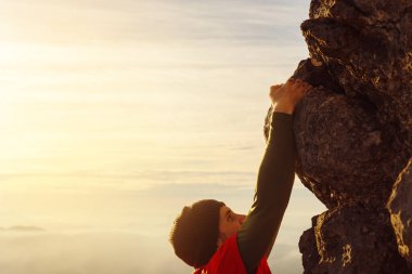 Yün şapkalı ve dövmeli beyaz adam gün batımında dağa tırmanıyor. ekstrem spor ve açık hava aktiviteleri.
