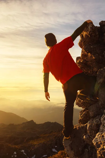 stock image man mountaineer and hiker perched on a mountain rock contemplating the beautiful sunset . sport and outdoor activity. man of adventure