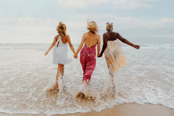 海岸の若い女性たちの多人種の集団の後ろから海に手を合わせて眺めます 友情と夏のコンセプト — ストック写真