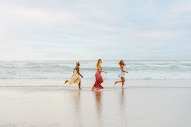 Sahilde koşan üç genç bayandan oluşan çok ırklı bir grup. Arkadaşlar birlikte sahilde yaz tatilinin tadını çıkarıyorlar. dostluk ve birlik.
