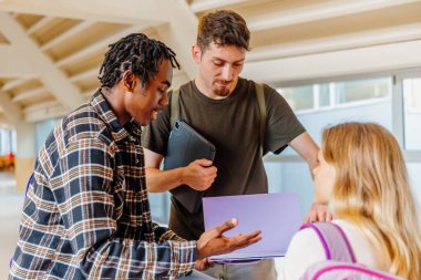 Sınavdan önce kampüs koridorunda sınıf notlarını gözden geçiren çeşitli, çok ırklı bir grup genç üniversite öğrencisi. Okula geri dön..